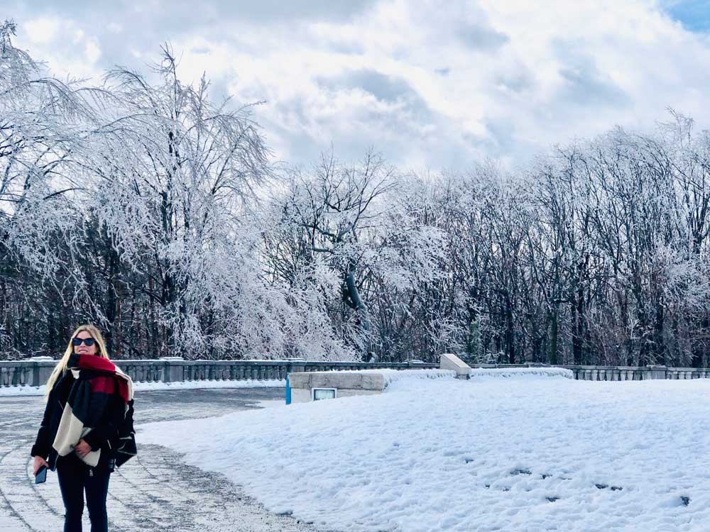 chica rubia abrigada posando para cámara y detrás un paisaje nevado